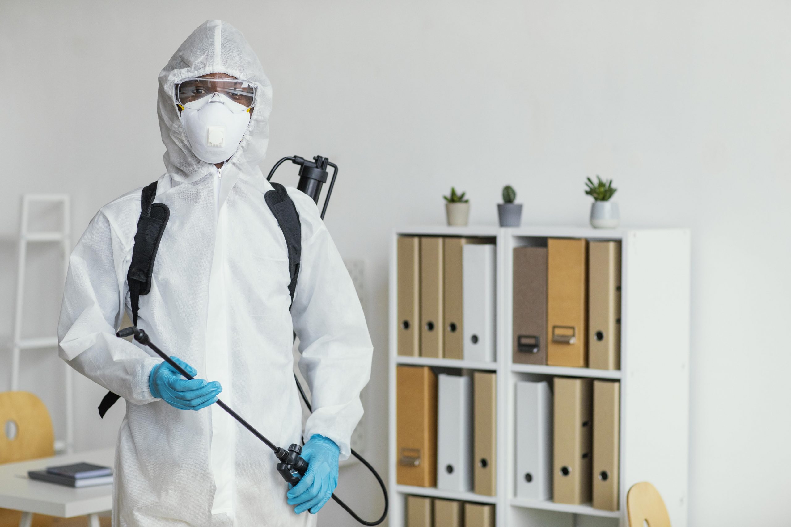 person-in-protective-suit-getting-ready-to-disinfect-room